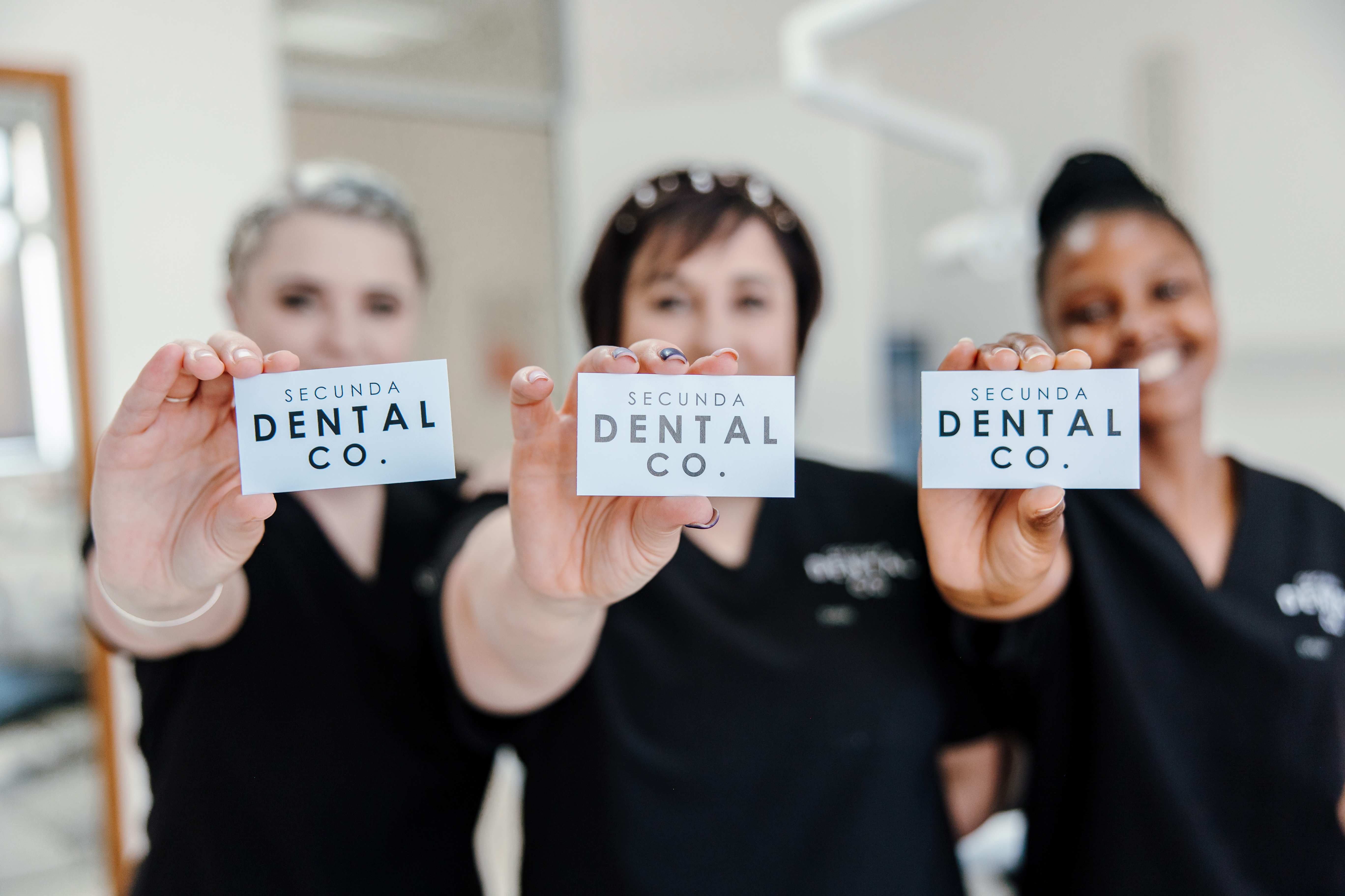 Team members holding Secunda Dental Co business cards